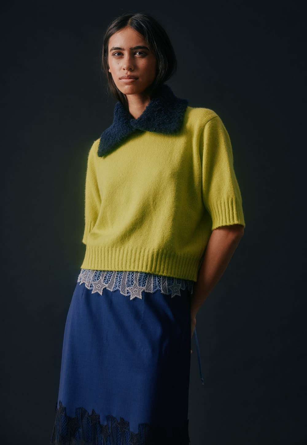 Model wearing the Antonia Zander Udra Top in Dusty Blue layered beneath the Niki Sweater, with the signature Celestial Lace subtly peeking out at the hem.